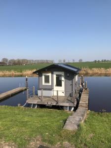 a small house on a dock on a body of water at Waterhut 2 Aduarderzijl in Feerwerd