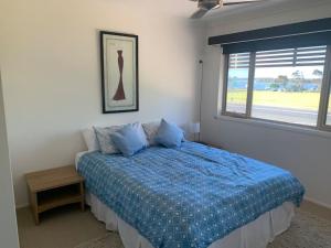 ein Schlafzimmer mit einem Bett mit blauer Decke und einem Fenster in der Unterkunft Riverview Apartment in Yamba