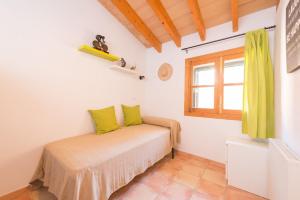 een slaapkamer met een bed met groene kussens en een raam bij Can Mayol in Fornalutx