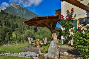 un patio con mesa y sillas bajo una sombrilla en Ferien im Steinberg, en Ramsau