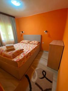 1 dormitorio con paredes de color naranja, 1 cama y 1 mesa en Apartment Jovicevic en Rijeka Crnojevića