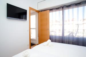 a bedroom with a bed and a tv and a window at Attic Bcn Central Terrace in Barcelona