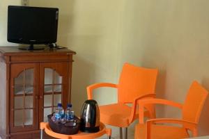 Habitación con 2 sillas de color naranja y TV. en KoolKost near Budi Mulia Siantar en Pematangsiantar