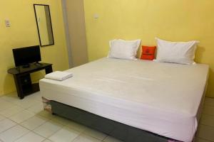 a large white bed in a room with a television at KoolKost near Budi Mulia Siantar in Pematangsiantar