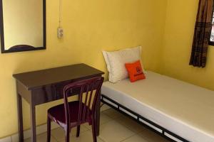 een kleine kamer met een bureau, een bed en een stoel bij KoolKost near Budi Mulia Siantar in Pematangsiantar