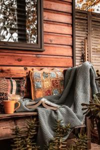 um cobertor e almofadas num banco em frente a uma casa em Piccolo Cosy Cottage with views em Hepburn