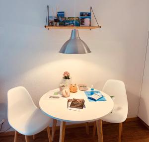 阿德爾博登的住宿－Studio im modernen Alpenstyle，一张带四把椅子和一盏灯的白色桌子