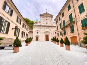 a church with a clock tower in a courtyard at HH Hermoso Housing SERRAVALLE in Serravalle Scrivia