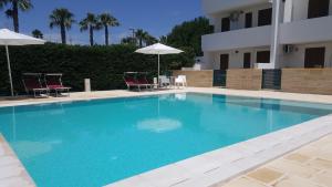 een groot blauw zwembad met 2 stoelen en parasols bij Villa piscina 24 posti letto in Torre dell'Orso
