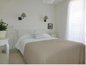 a white bedroom with a bed and a window at Apartamento céntrico cerca de la playa in L'Ametlla de Mar