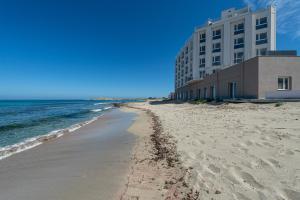 a beach with a building and the ocean at Hotel Punta Tipa in Trapani