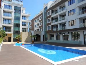 an apartment with a swimming pool in front of a building at Sea View Apartment free parking in Primorsko