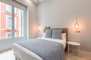 een witte slaapkamer met een bed en een raam bij Arenal Suites Gran Vía in Madrid