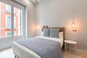 a white bedroom with a bed and a window at Arenal Suites Gran Vía in Madrid