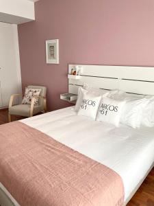 ein Schlafzimmer mit einem großen weißen Bett und einem Stuhl in der Unterkunft Arcos 61 in Tomar