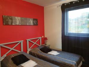 2 camas en una habitación con paredes rojas y ventana en Laouchet Le Hameau des Grands Lacs, en Parentis-en-Born