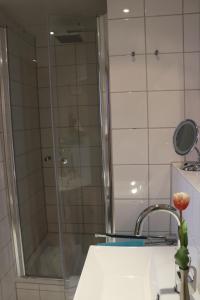 a shower with a glass door next to a sink at Gästehaus Germania in Wangerooge