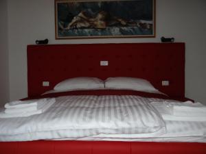 duże łóżko z czerwonym zagłówkiem i białymi poduszkami w obiekcie Relax Center Olimian w mieście Podčetrtek