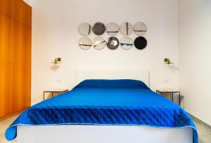 een slaapkamer met een bed met blauwe lakens en pannen aan de muur bij Damè - Accommodation Amalfi Coast in Maiori