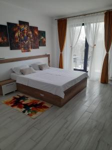 a bedroom with a large bed and a wooden floor at Beach Residence 10 metri pana la plaja in Năvodari