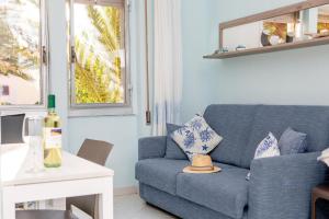 un divano blu in soggiorno con finestra di Bilocale il Nido Blu a Santa Teresa di Gallura