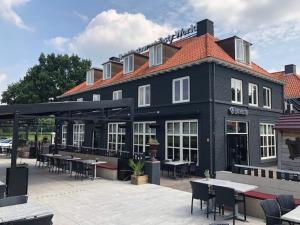 un edificio negro con mesas y sillas delante en Tasty World en Hoogerheide