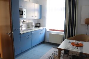 eine kleine Küche mit blauen Schränken und einem Tisch in der Unterkunft Gästehaus Germania in Wangerooge