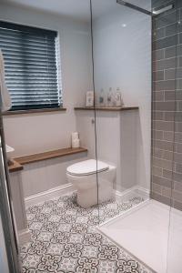 a bathroom with a toilet and a glass shower at Riverbank Cottage in Ironbridge