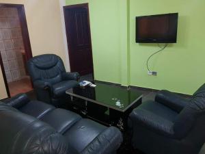 sala de estar con muebles de cuero negro y TV de pantalla plana en LE MILAN ( appartements et chambres meublés ) en Douala