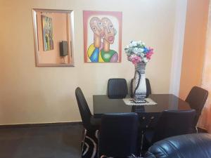 un comedor con una mesa y un jarrón con flores en LE MILAN ( appartements et chambres meublés ) en Douala