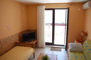 een woonkamer met een bed, een tv en een raam bij Apartments Pine Diver in Pinezici