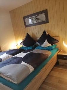 a bed with black and white pillows on it at Traumblick Bayerischer Wald, Pool & Sauna, Getränke, Klimaanlage in Freyung