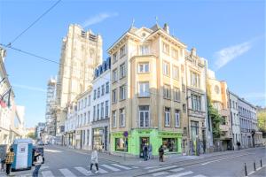 アントワープにあるLily Apartment. Historic Center of Antwerpの通りを横断する人々のいる街路の高い黄色の建物