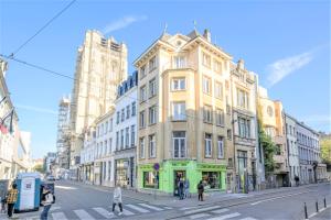 a tall yellow building on a city street with people crossing the street at Penth A Apartment in Heart of Antwerp in Antwerp