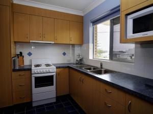 a kitchen with a stove and a sink and a window at Anchorage 7 in Tuncurry