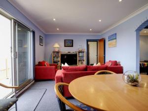 a living room with red couches and a wooden table at Anchorage 7 in Tuncurry