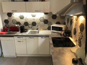 a white kitchen with a sink and a microwave at Suite Darcy & Spa in Dijon