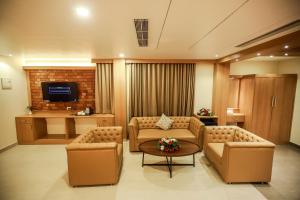 a living room with two couches and a tv at Nesma Palace in Kannur