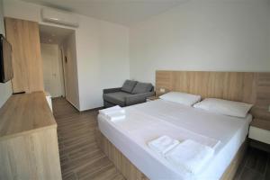 卡薩米里的住宿－Hotel Ksamili，卧室配有一张白色大床和一把椅子