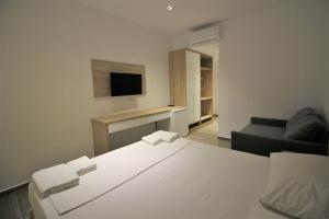um quarto com uma cama branca e um sofá em Hotel Ksamili em Ksamil