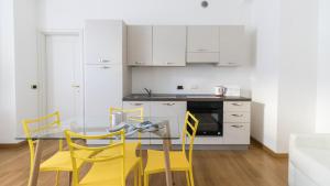 サンレモにあるItalianway-Villa Mafaldaのガラステーブルと黄色の椅子付きのキッチン