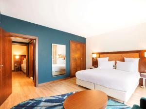 a bedroom with a white bed and a blue wall at Mercure Istanbul Bakirkoy in Istanbul