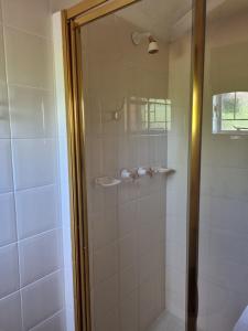 a shower with a glass door in a bathroom at Camelia Guest House in Universitas