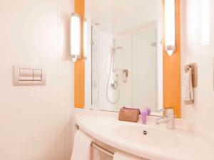 a white bathroom with a sink and a mirror at ibis London Elstree Borehamwood in Borehamwood