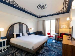 Habitación de hotel con cama, escritorio y sillas en Aparthotel Adagio Paris Haussmann Champs Elysées, en París