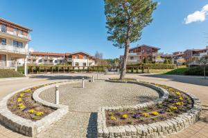 a circle of flowers in a park with a tree at Grand Apartments - Neptun Park. in Gdańsk