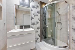 a white bathroom with a sink and a shower at Grand Apartments - Neptun Park. in Gdańsk
