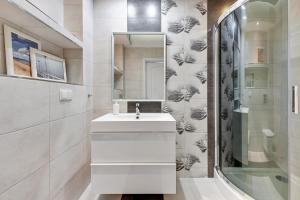 a white bathroom with a sink and a mirror at Grand Apartments - Neptun Park. in Gdańsk
