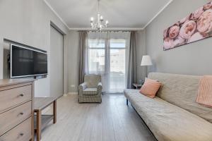 a living room with a couch and a flat screen tv at Grand Apartments - Neptun Park. in Gdańsk