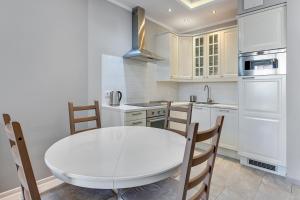 a white kitchen with a white table and chairs at Grand Apartments - Neptun Park. in Gdańsk